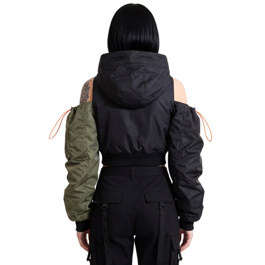 Rear view of RAVEDRIP Women's Avant-Garde Deconstructed Cropped Bomber Jacket, solid black nylon back with high-volume hood, cold-shoulder cutouts showing shoulders, asymmetric ruched sleeves in olive green and black with neon orange tactical bungees, high-key e-commerce studio fashion photography.