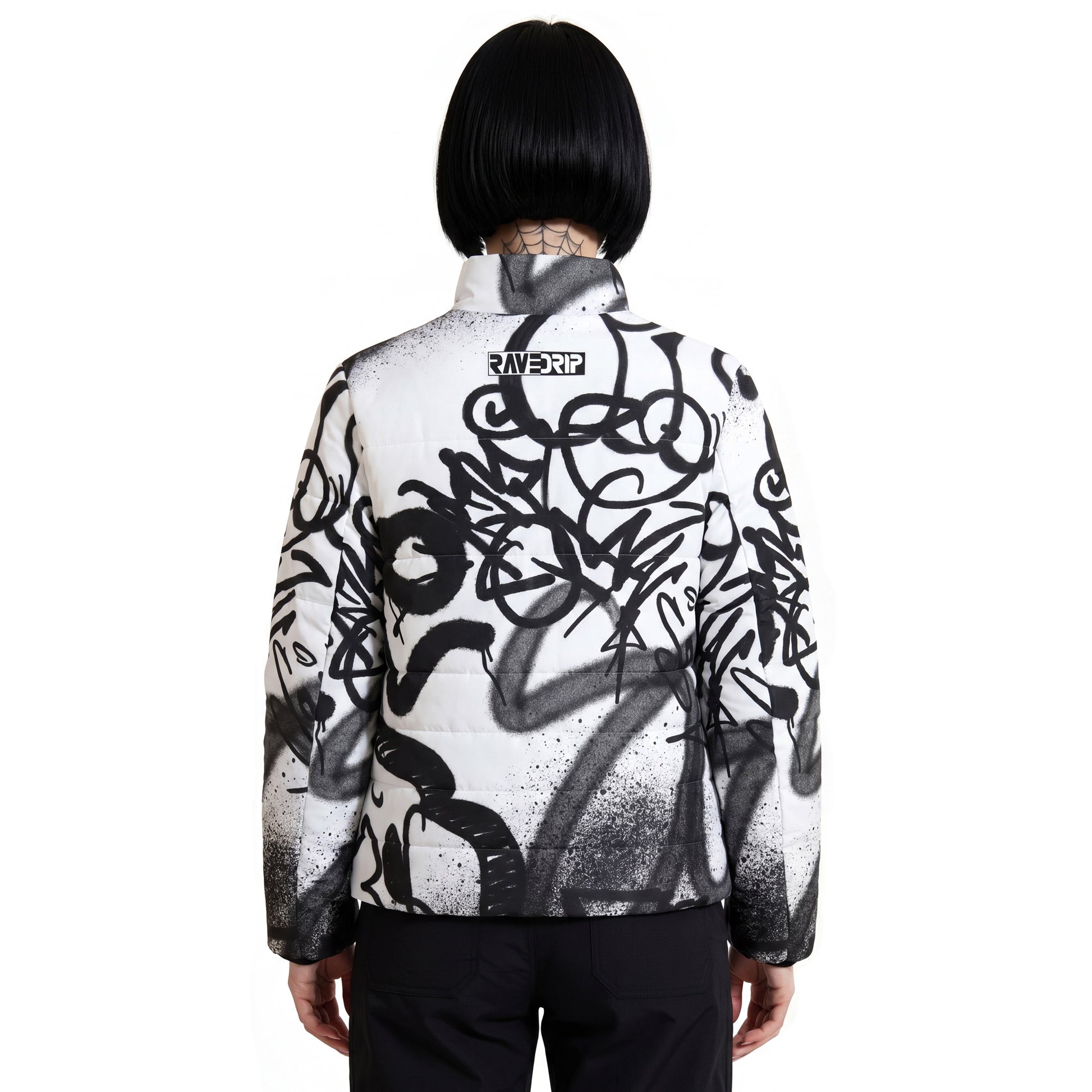 Back view of RAVEDRIP Padded Puffer Jacket featuring minimalist black and white logo block on the upper back, white insulated streetwear coat with chaotic black street art spray paint graphics, alternative female model with symmetrical black bob haircut.