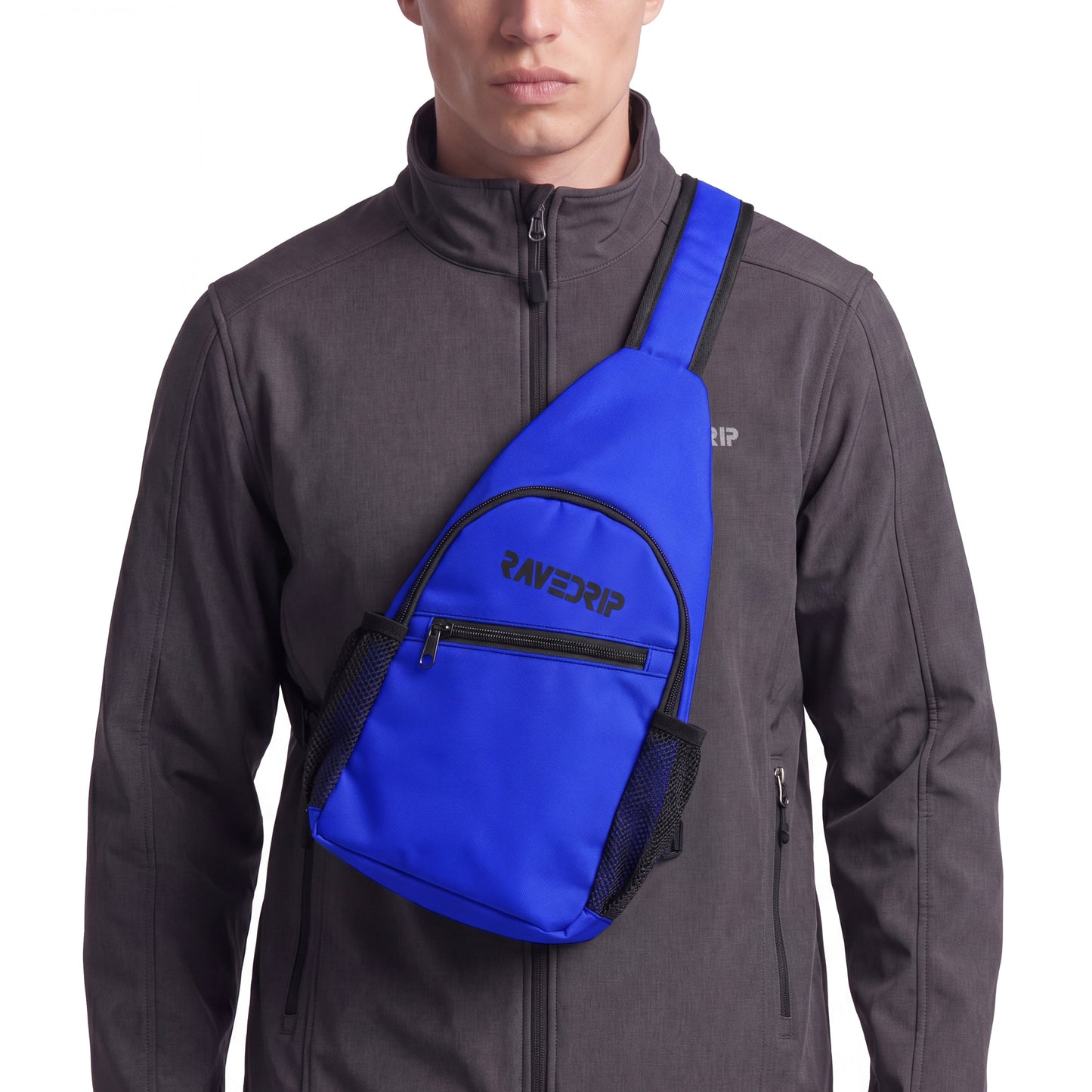 Close-up cropped studio shot of a RAVEDRIP royal blue canvas sling chest bag with a vertical teardrop design. The bag features a black zipper, mesh side pockets, and a black logo, worn front-facing over a technical charcoal grey softshell jacket. Premium e-commerce techwear product photography.
