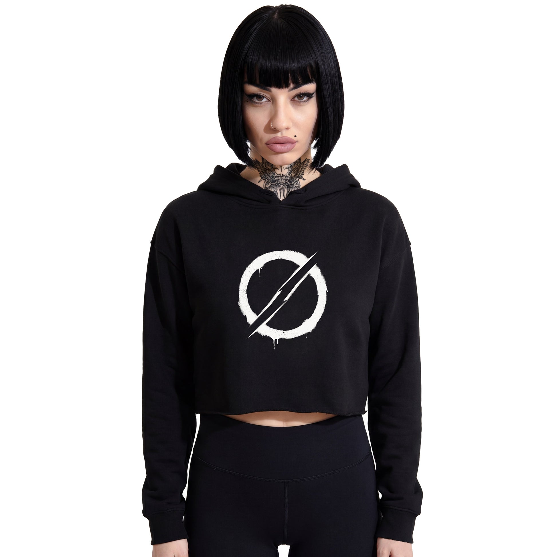Front-facing studio product shot of a female model with a black bob haircut wearing a RAVEDRIP black cropped hoodie with hidden drawstrings. Features a bold white grunge stencil circle and slash graphic on the chest. Paired with tight high-waisted black leggings against a solid white background. Underground rave streetwear style.