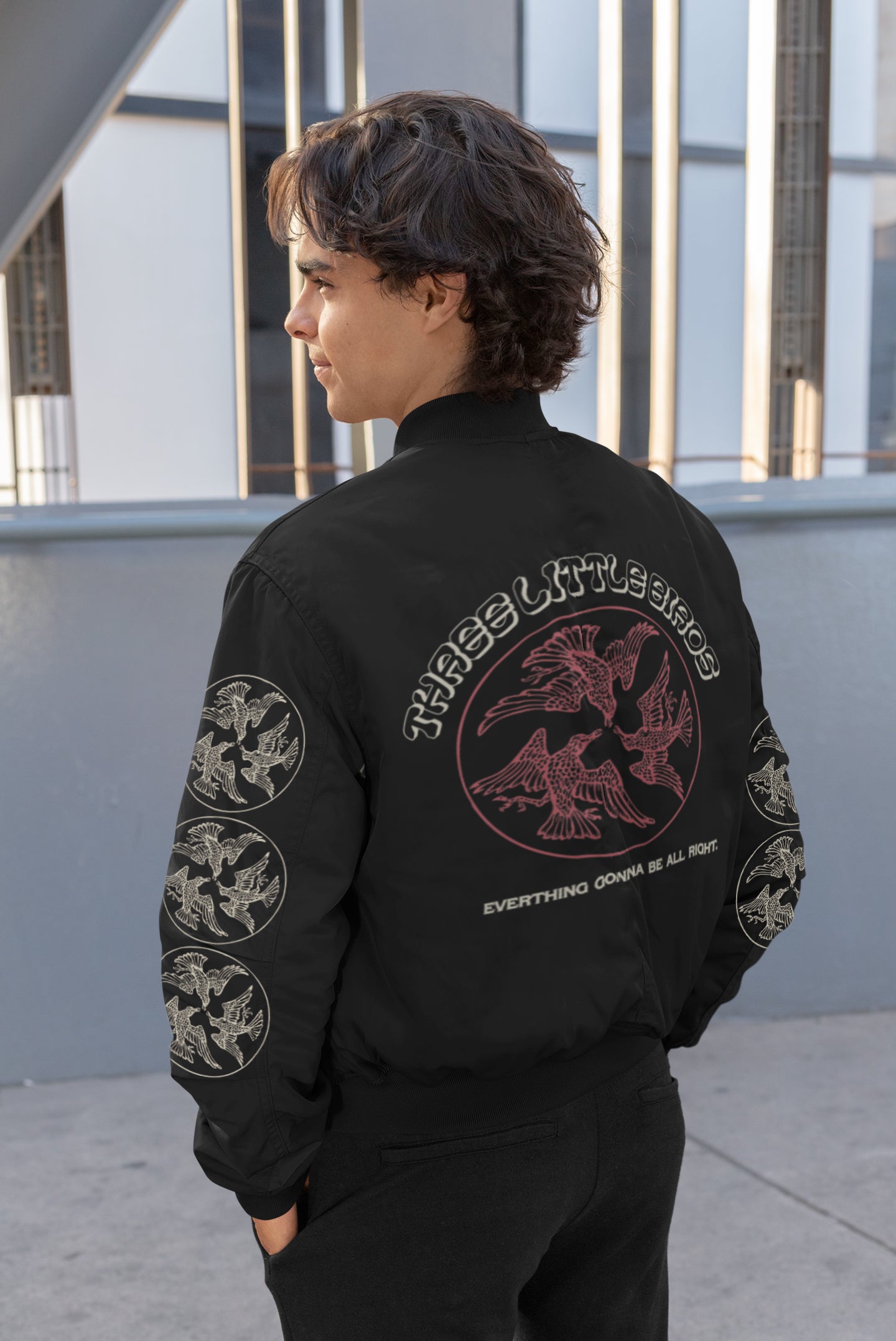Men's Graphic Bomber Jacket with 'Three Little Birds' all-over print design, featuring rib knit cuffs and front pockets for a trendy and comfortable fit. On a model