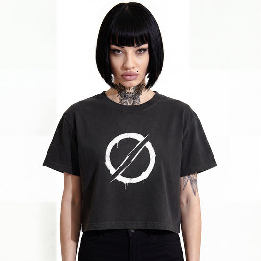 RAVEDRIP The Deviant heavyweight boxy cropped tee in faded black, wide square fit women's streetwear t-shirt featuring a white distressed circular slash symbol graphic print on the chest, worn by alternative female model.