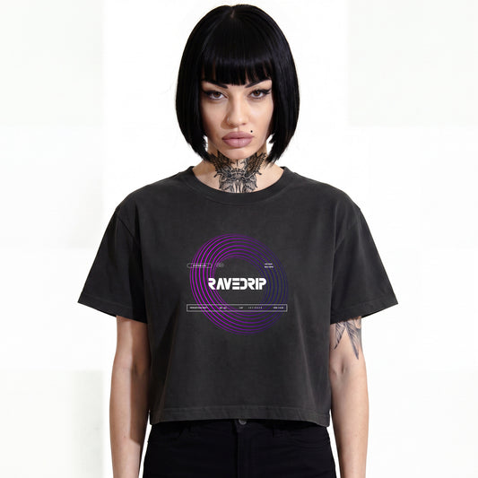 RAVEDRIP Vortex heavyweight boxy cropped tee in faded black, premium wide square fit women's streetwear t-shirt with short mid-bicep sleeves and purple circular vortex graphic print, worn by alternative female model with black bob haircut and neck tattoo, e-commerce studio catalog photography on white background.