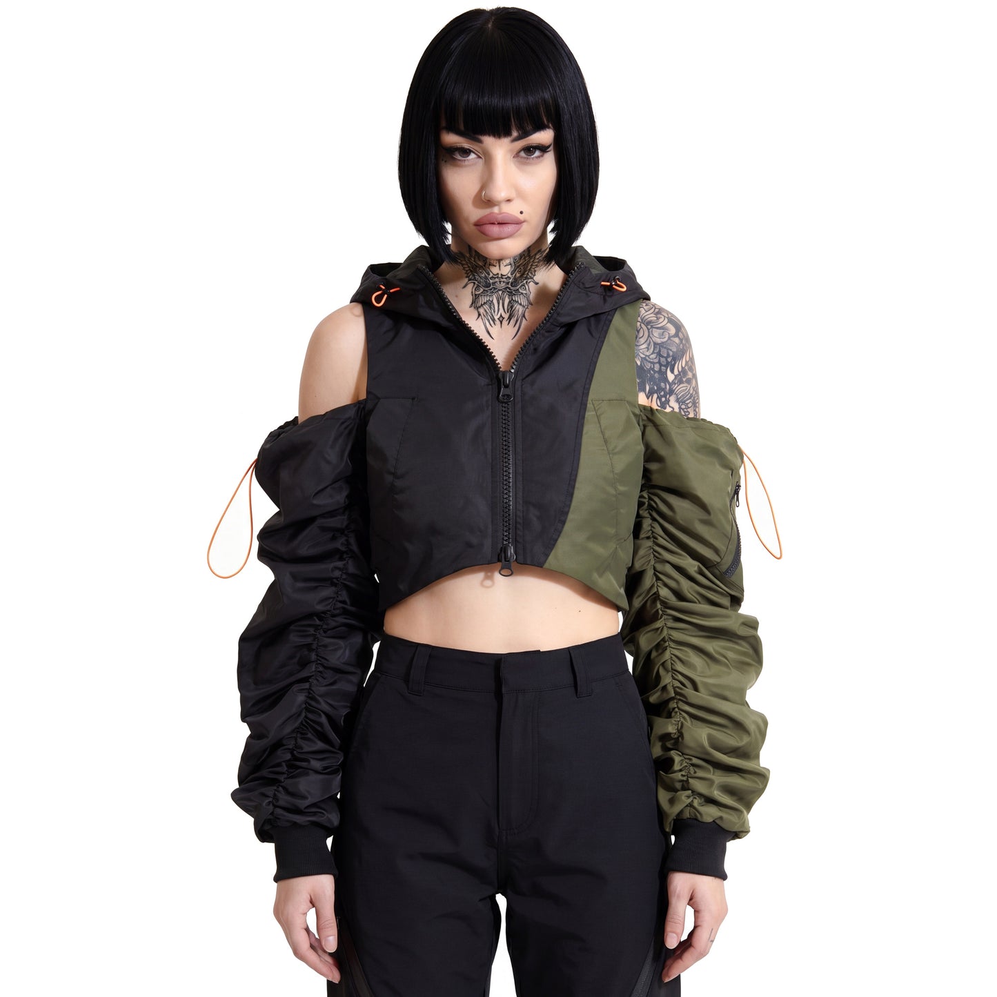 RAVEDRIP Women's Avant-Garde Deconstructed Cropped Bomber Jacket, asymmetric split-color black and olive green nylon techwear outerwear with cold-shoulder cutouts and heavily ruched sleeves, featuring neon orange tactical bungee cords, worn by alternative female model with neck tattoo, high-key e-commerce studio catalog photography.