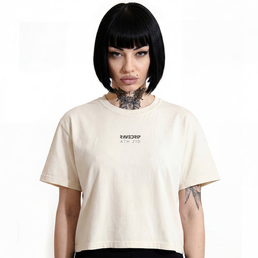 RAVEDRIP women's essential boxy t-shirt in solid Ivory color, relaxed fit streetwear tee with minimalist grey logo typography on center chest, worn by female model with alternative neck tattoos and black bob haircut, studio e-commerce catalog photography on pure white background.