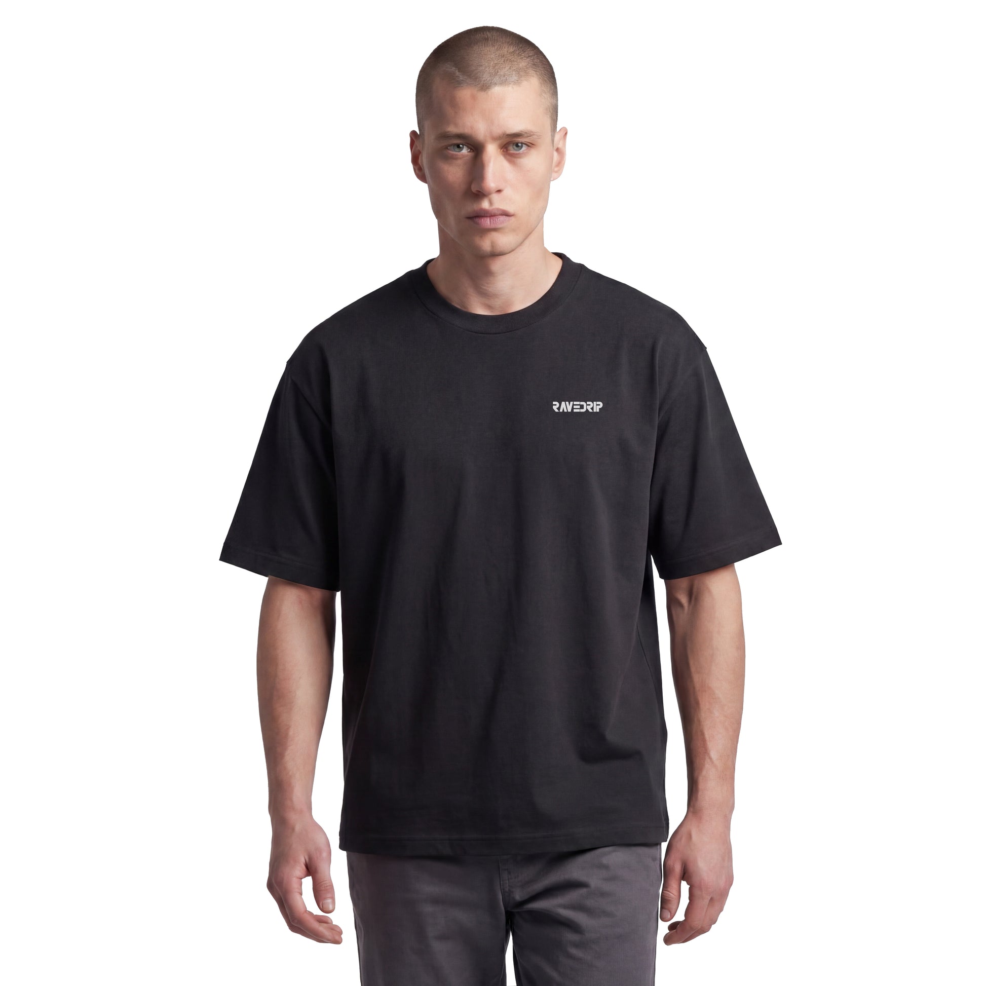 Studio lookbook photography of male model wearing the RAVEDRIP 'Seraphim Cyber-Sigil' ultra-heavyweight black oversized tee. Showcases the rigid architectural drape, dropped shoulders, and subtle front chest micro-logo, styled against a clean minimalist white studio background.