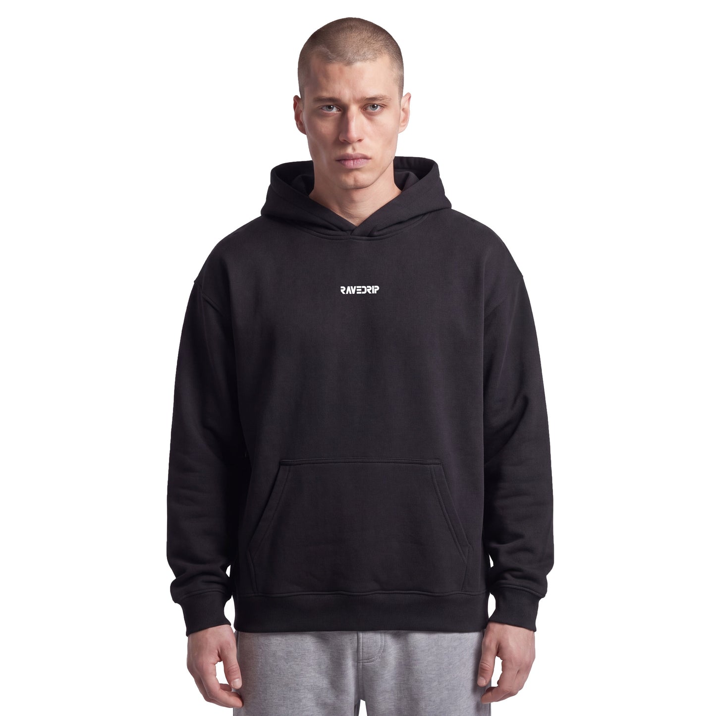 Studio lookbook portrait of male model wearing the RAVEDRIP Core Relaxed heavyweight hoodie in Black. The 9.4oz AS Colour fleece hoodie features a drawstring-less double-layer hood, dropped shoulders, and a small minimalist white logo printed on the high chest, styled for an edgy, iconic streetwear look.