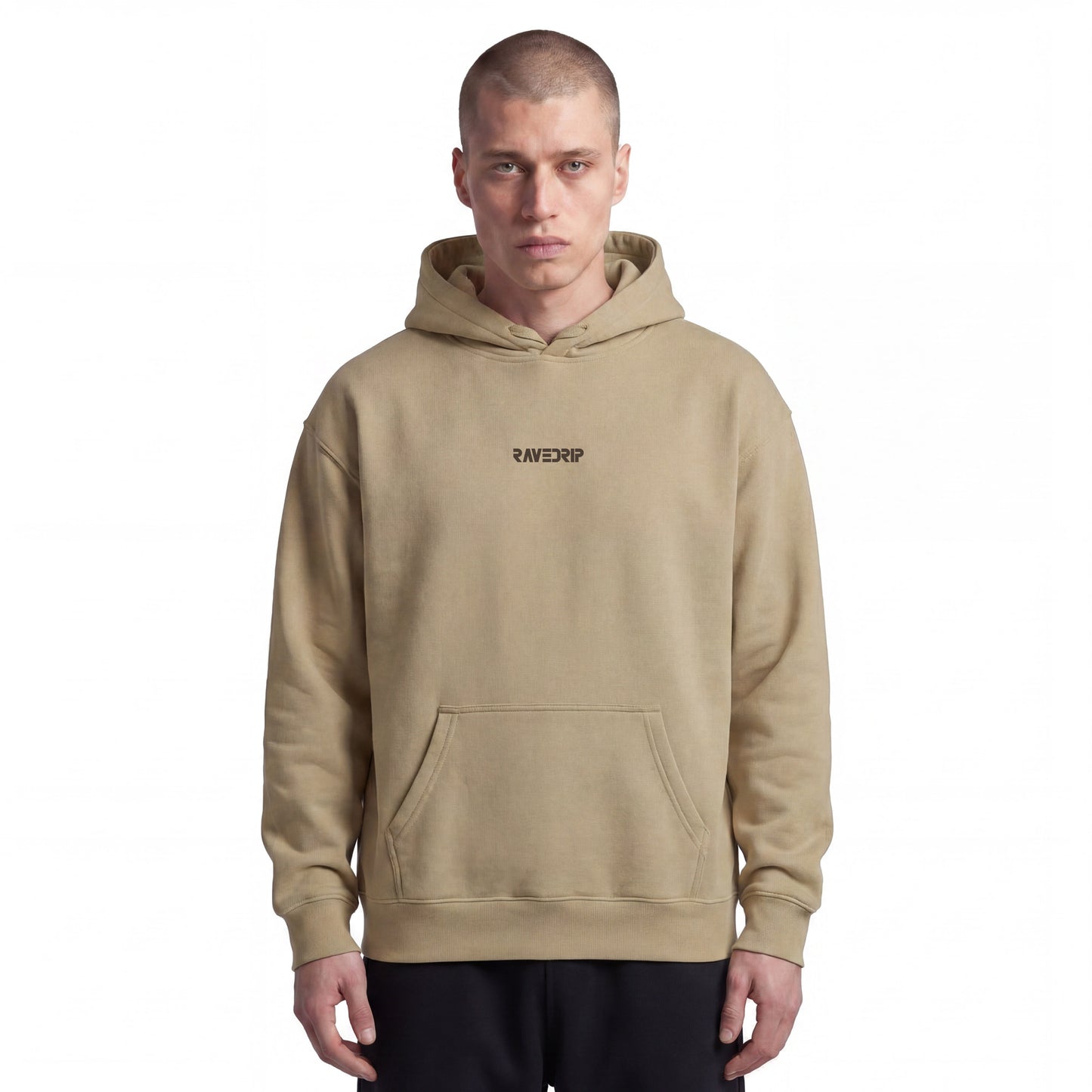 Studio lookbook portrait of male model wearing the RAVEDRIP Hammer Maxweight heavyweight hoodie in Tan. The 10.5oz cotton-rich fleece hoodie features a relaxed boxy fit, dropped shoulders, hidden tucked-in drawstrings, and a small minimalist black embroidered logo centered on the upper chest, styled with relaxed black sweatpants.