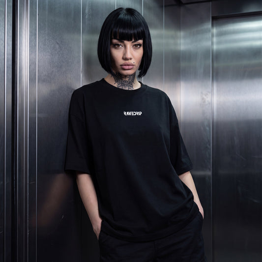 Woman wearing black oversized Core Matrix Boxy Tee with Rave Drip logo in metallic elevator